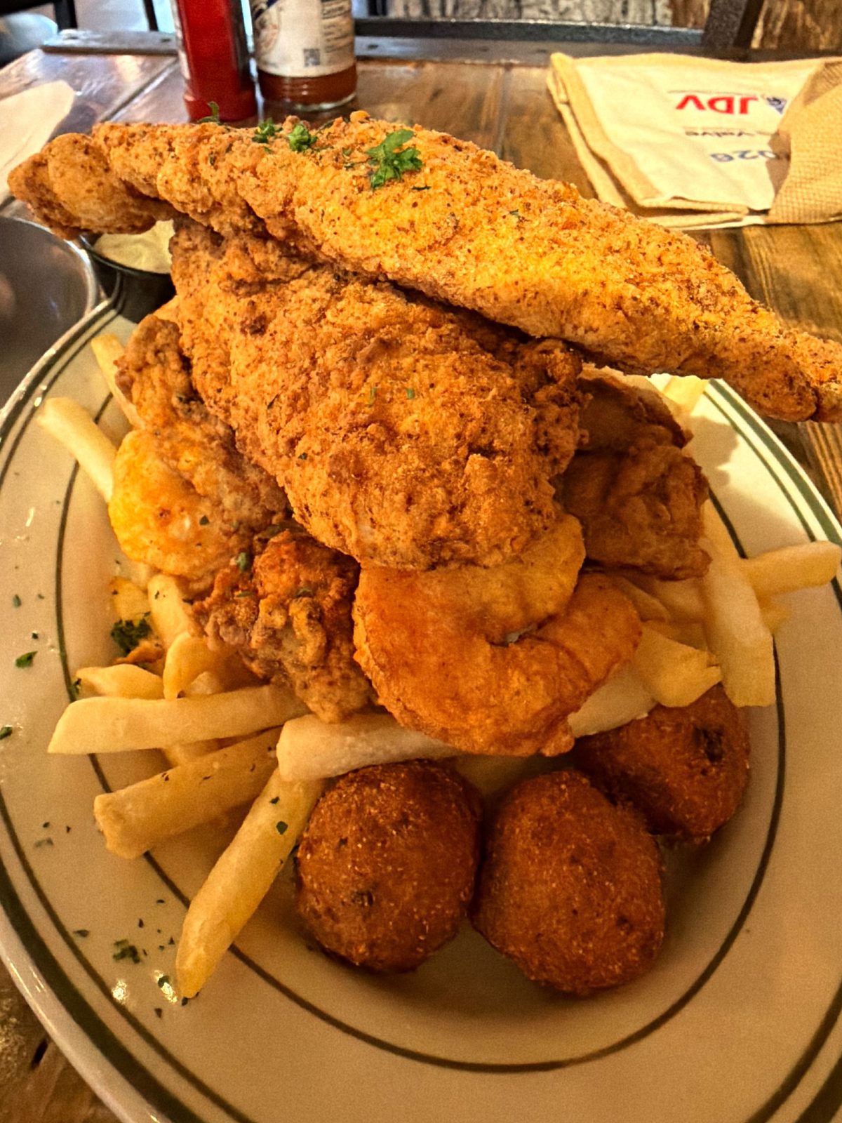 A towering plate of fried fish, shrimp, fries and hush puppies